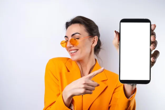 young woman trendy stylish glasses bright orange oversized jacket white background holds phone with blank white screen 343596 8184